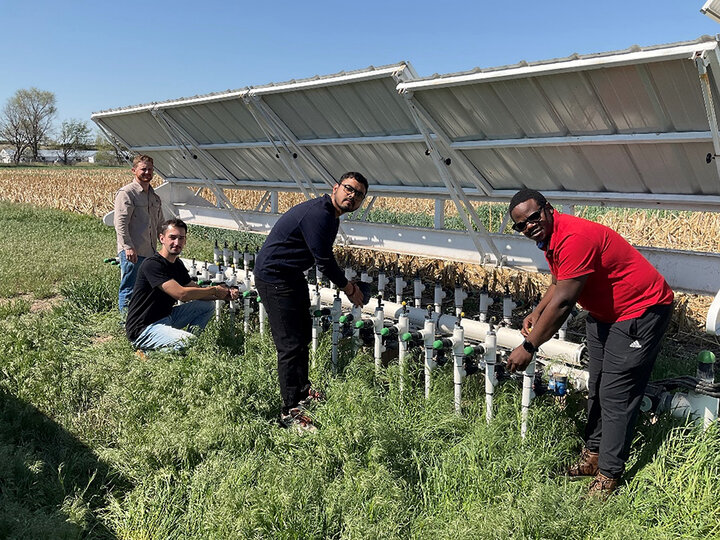 three men installing components of irrigation system in field