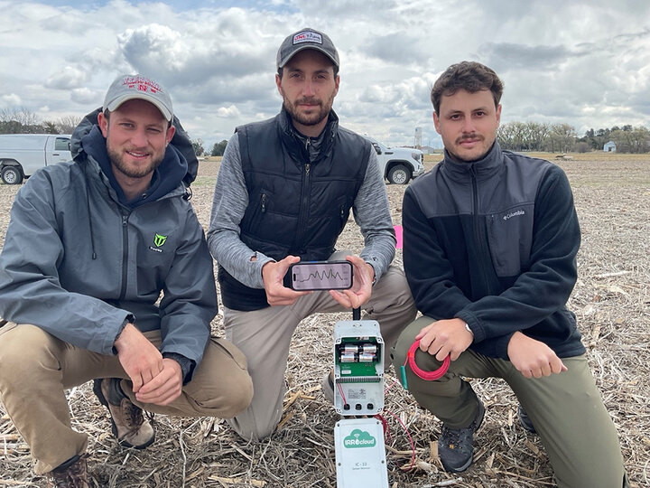 three men pose with phone and sensor