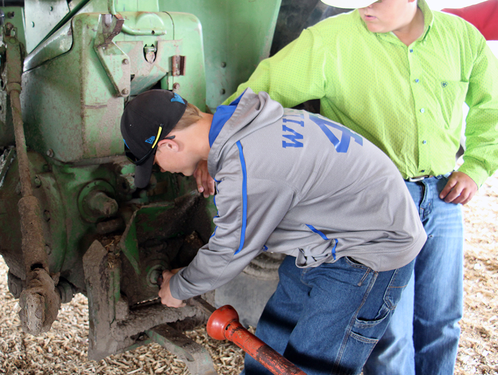 Two youth practicing proper connection procedures for a tractor PTO drive.