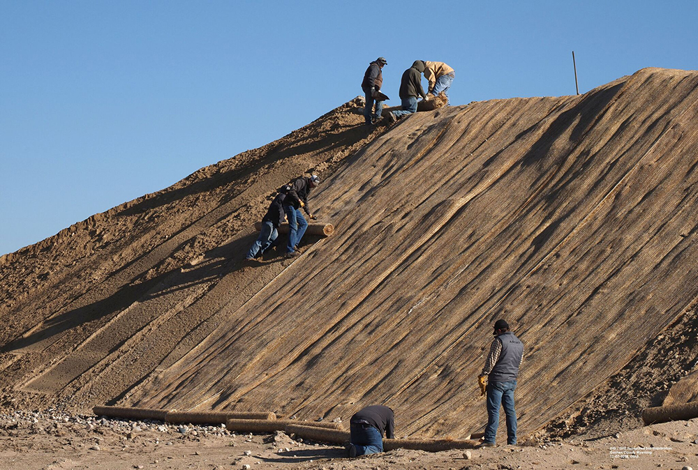 Workers cover piles of excavated dirt from the site of the Tunnel 2 collapse to avoid erosion.
