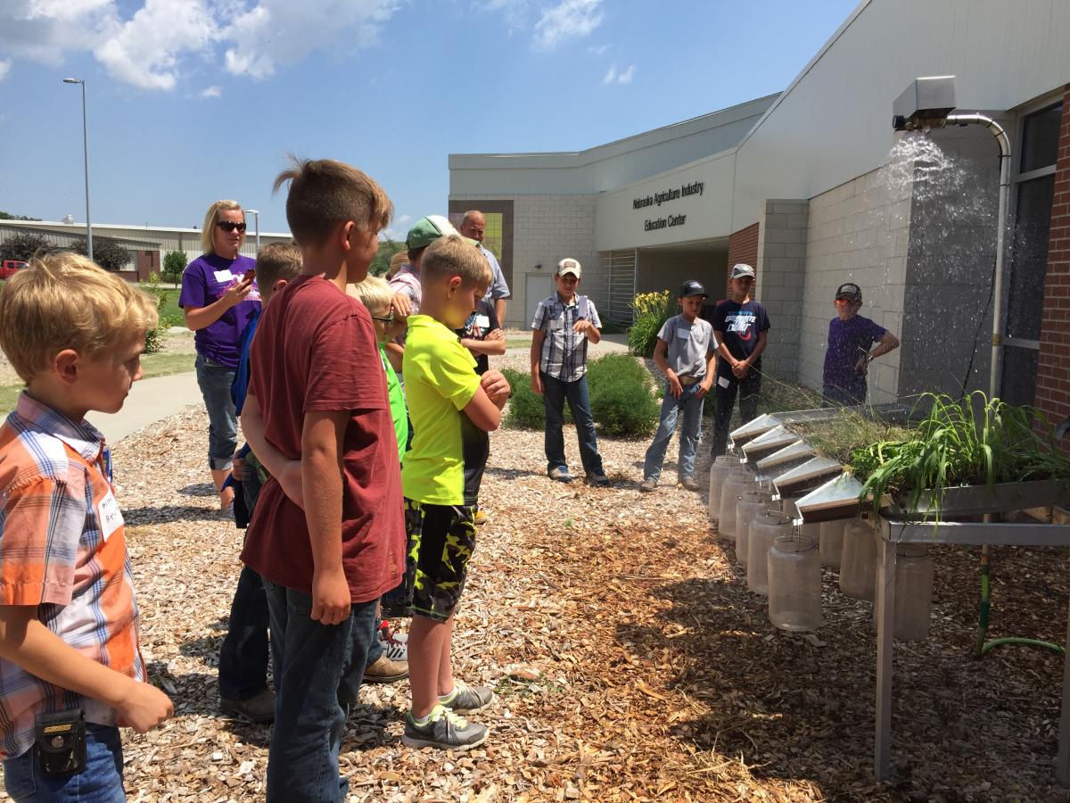 Youth viewing a rainfall simulator at the 2018 Youth Field Day