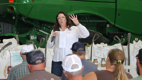 woman speaking to audience near tractor