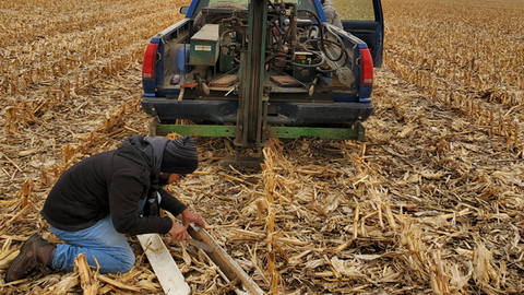 Field technician collects a soil core sample in a corn residue field using a truck-mounted probe during on-farm soil sampling in Nebraska.