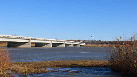 With Niobara, Nebraska, in the distance, the Mormon Canal Bridge spans the Niobrara River at the confluence of the Niobrara and Missouri rivers. The bridge was washed out during the 2019 flood, separating Niobrara residents from many of their neighboring communities.