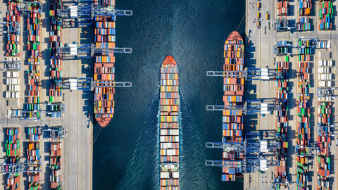 An overhead view of three container ships in a canal.