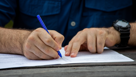 man filling out form on table