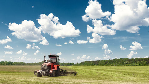 tractor harvests hay in pasture
