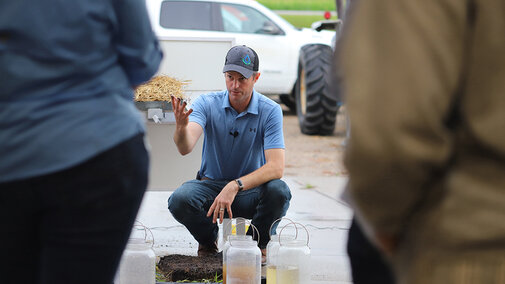 Aaron Hird gestures to soil and water samples