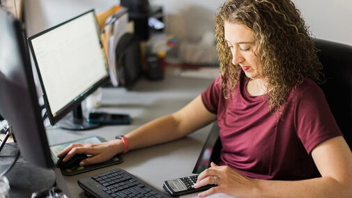 Woman at computer using calculator