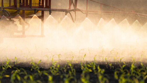 Tractor spraying pesticide onto field