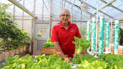 Stacy Adams standing behind crops in greenhouse