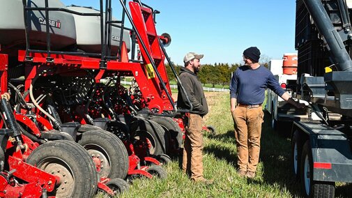 Two farmers conversing near farm equipment