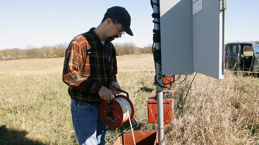 Man holds cable reel above water well