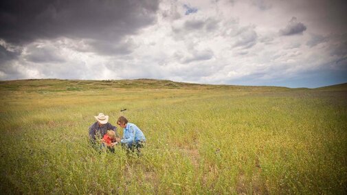 Man, woman and child kneel in pasture