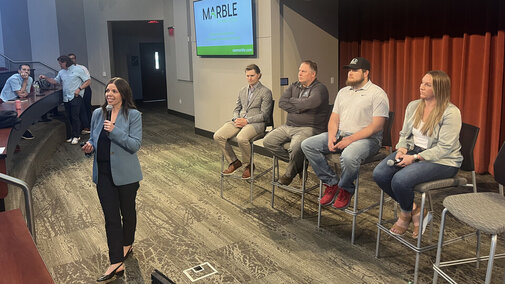 Woman stands in front of panel sitting on stage