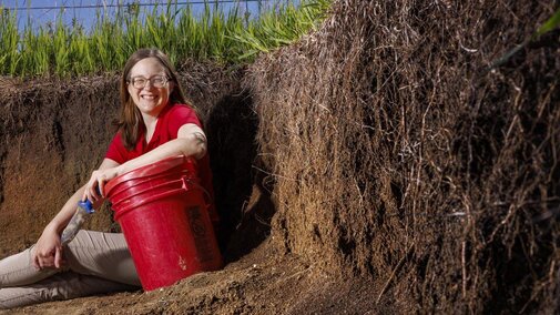 Woman sits near wall of soil