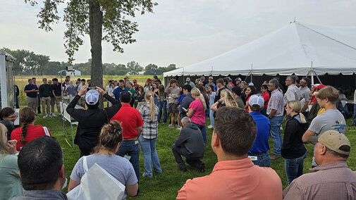 Large group of people surround Nathan Mueller during live rainfall simulation