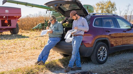 Two men look at paperwork near field