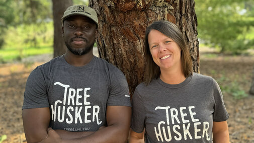 Man and woman pose in front of tree