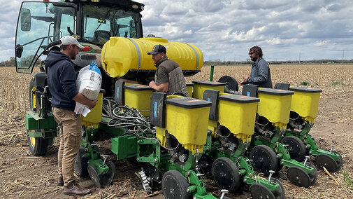Three men work at a planter in the field