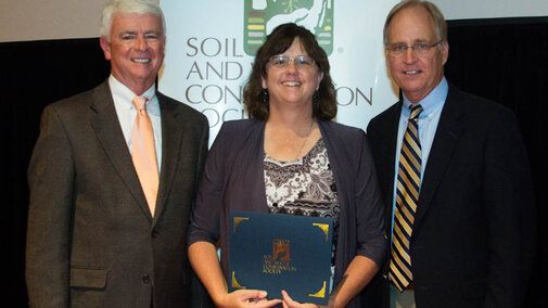 NRCS Resource Conservationist Claudia Stevenson receiving the International SWCS Commendation Award at the international meeting in July from (left) association executive director Jim Guilliford and association president Jon Scholl. 