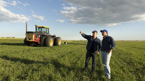 two farm employees discuss plans in a field