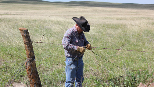 Rancher fixing a fence damaged by spring weather