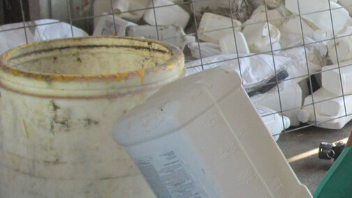 Lucas Burch wears gloves and safety glasses while triple rinsing a pesticide container.