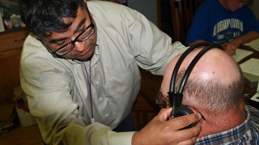 A researcher from the UNMC Center for Public Health works with a Nebraska farmer to fit protective ear wear.