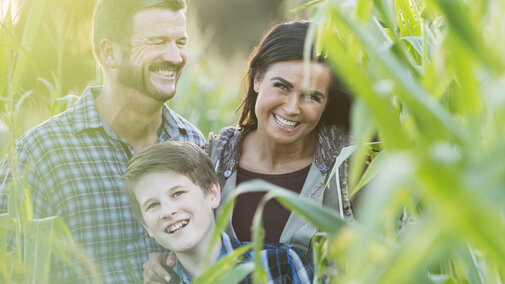 A happy family standing in a corn field