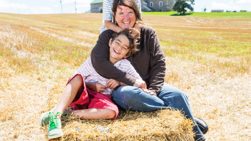 Woman farmer with children on hay bale