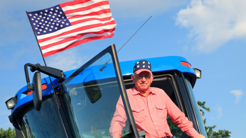 Farmer in tractor below flag