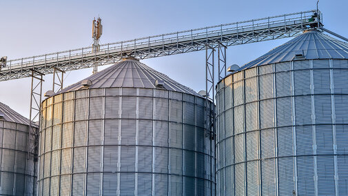 Silver grain bins stacked closely together under blue sky