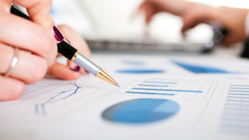 Woman holds pen above bar chart on paper