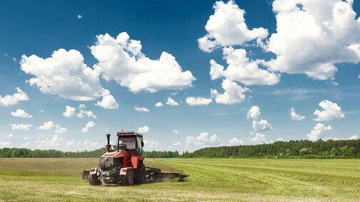 tractor harvests hay in pasture