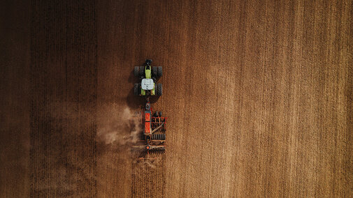 Tractor pulls planter through field during wheat planting