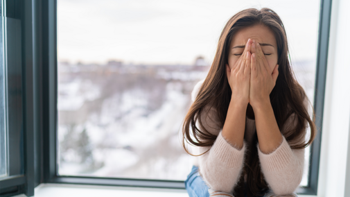 Woman with signs of stress in front of window during winter