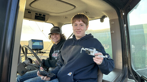 youth in tractor cab holding drone