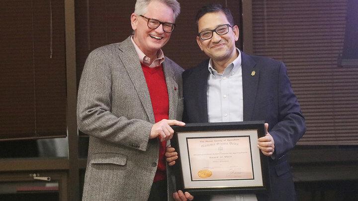 two men pose for photo with award