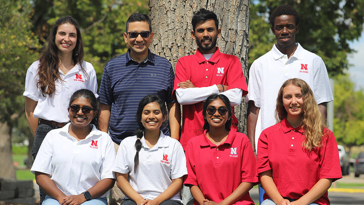 Group photo of seven Nebraska Soil Science Lab interns and their supervisor, standing and sitting outdoors in front of a tree.