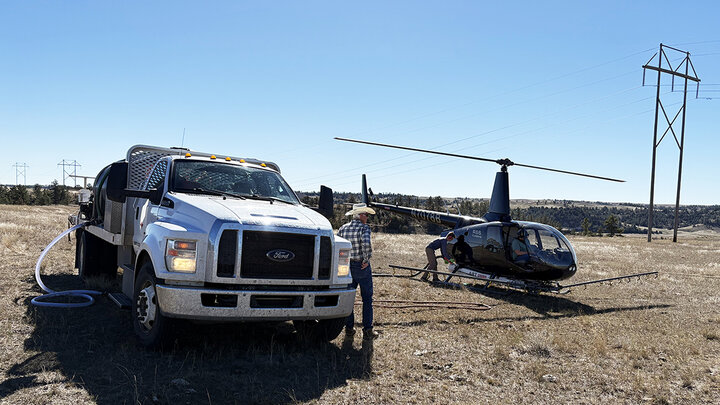 Helicopter prepares to aerially apply herbicide for cheatgrass control on rangeland in Nebraska’s Wildcat Hills, with support truck on site.