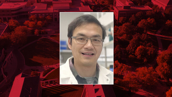 Color portrait of Huang Li, research assistant professor of biochemistry and Heuermann Research Fellow at the University of Nebraska–Lincoln, on a red campus background.