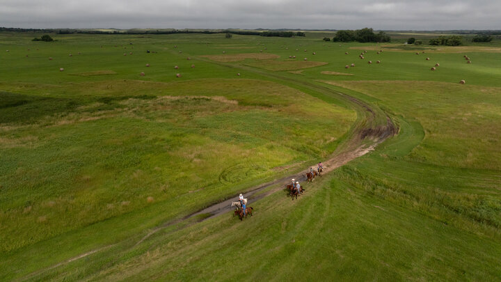 An aerial photo of six ranchers riding horses in the Nebraska Sandhills.