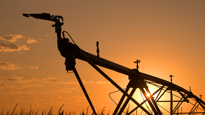 closeup of center pivot in corn field at sunset