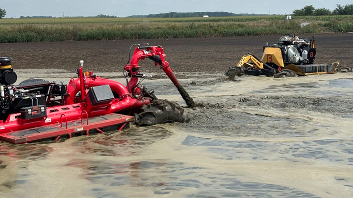 Manure application equipment operates in a field, with machinery pumping and incorporating liquid manure during a live demonstration on nutrient management practices.