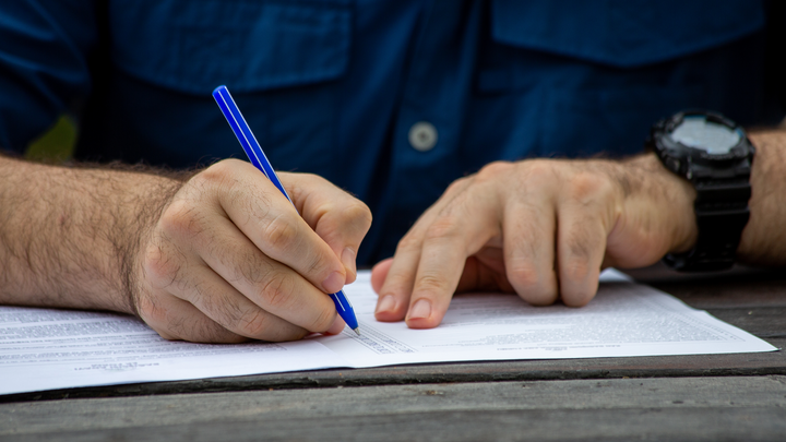 man filling out form on table