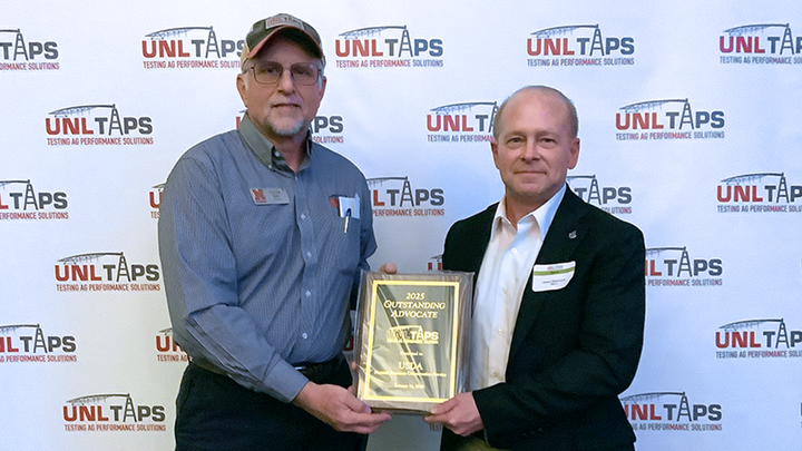 Chuck Burr presents the 2025 Outstanding TAPS Advocate award plaque to James Huntwork of USDA Natural Resources Conservation Service at the UNL TAPS awards banquet.