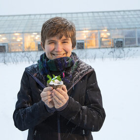 Rebecca Roston, assistant professor of biochemistry, holds a pea plant outside the Beadle Hall greenhouses. Roston, who recently earned a National Science Foundation CAREER award, is studying how more than 30 species of plants respond to freezing. (Photo by Craig Chandler)