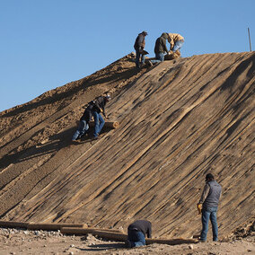 Irrigation District staff lay down a fabric mat to reduce erosion of excavated soil.