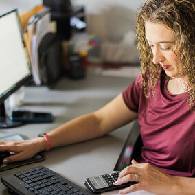 Woman at computer using calculator